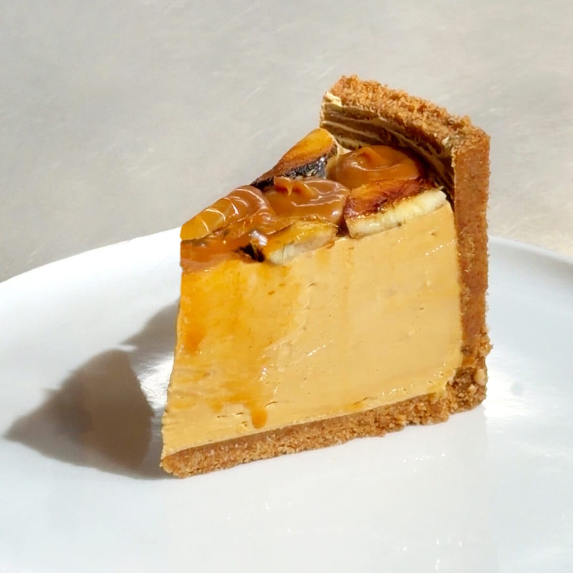 Small slice of Banoffee Cheesecake with creamy caramel filling and banana topping by Cheesecake Family