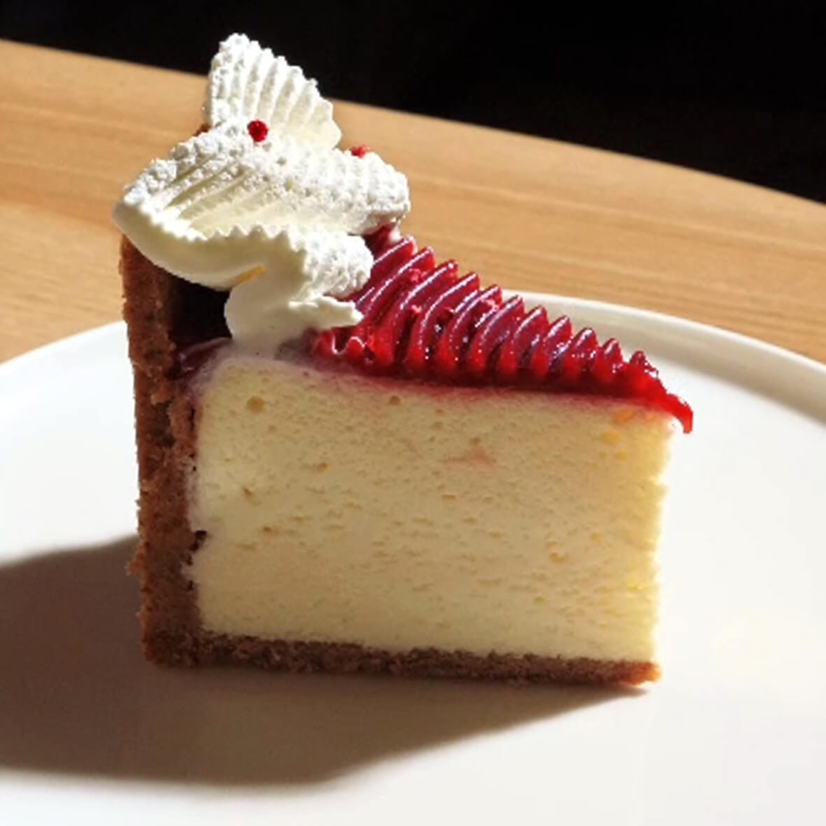 Шматочок класичного чизкейка «Нью-Йорк» Cheesecake Family з ніжною кремовою текстурою та малиновим шаром.