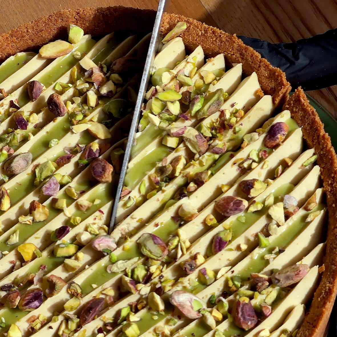 Pistachio Cheesecake — top view cutting cheesecake with cream and pistachios