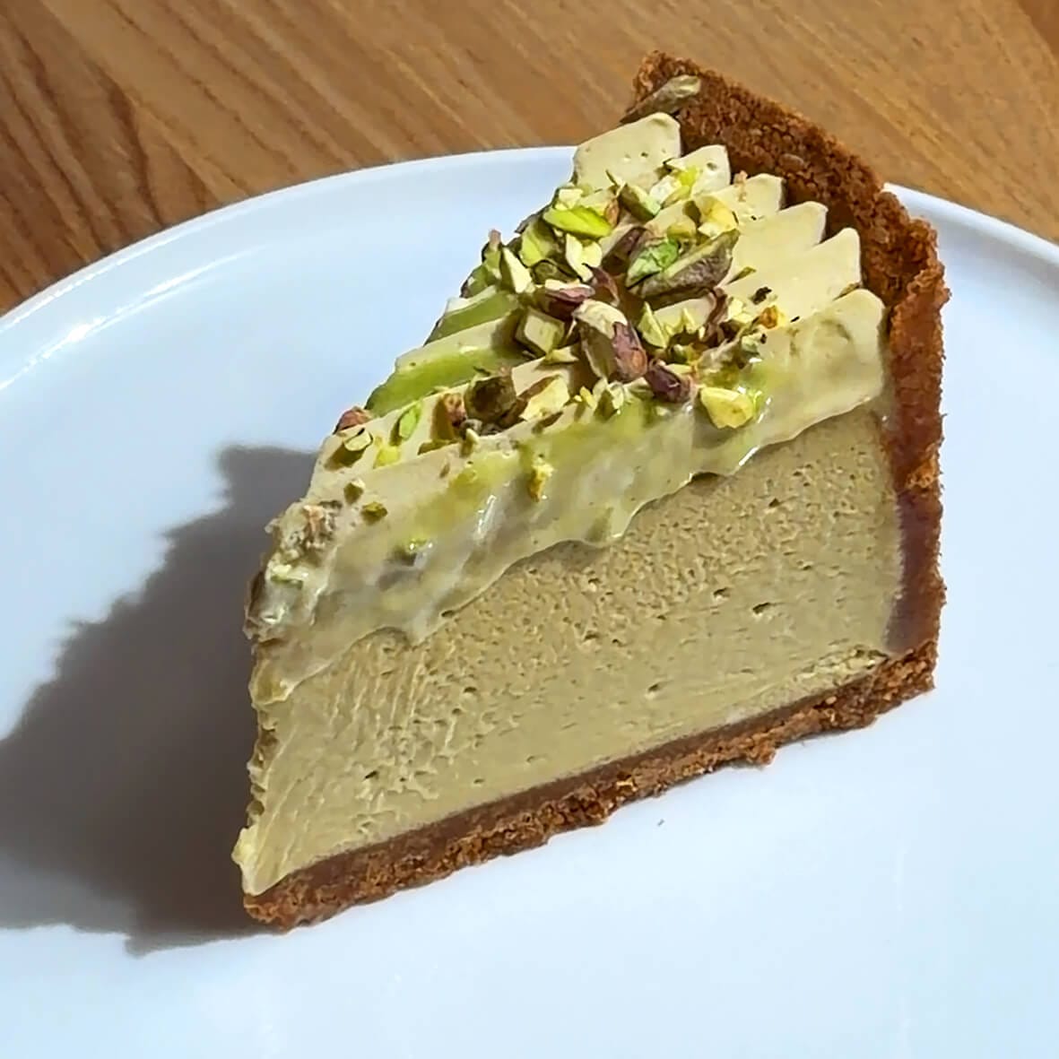 Шматочок фісташкового чизкейка крупно вид зверху Cheesecake Family